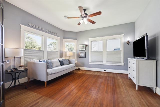 living room featuring visible vents, wood-type flooring, a ceiling fan, and baseboards