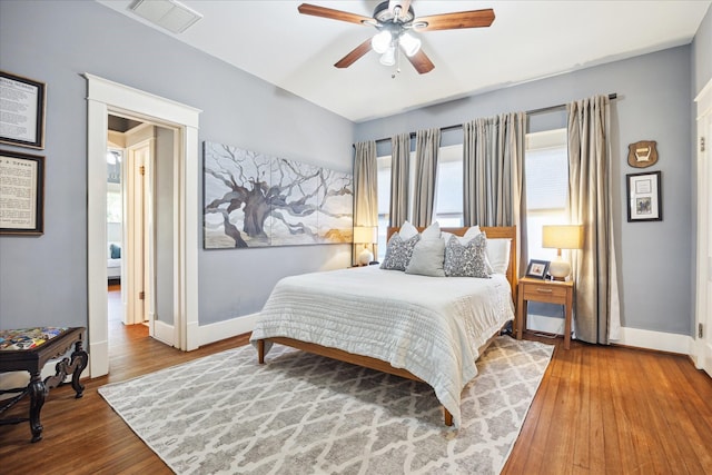 bedroom featuring ceiling fan, wood finished floors, visible vents, and baseboards