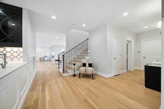 entrance foyer with recessed lighting, baseboards, light wood finished floors, and stairs