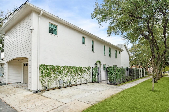 view of side of home featuring a lawn, an attached garage, and fence