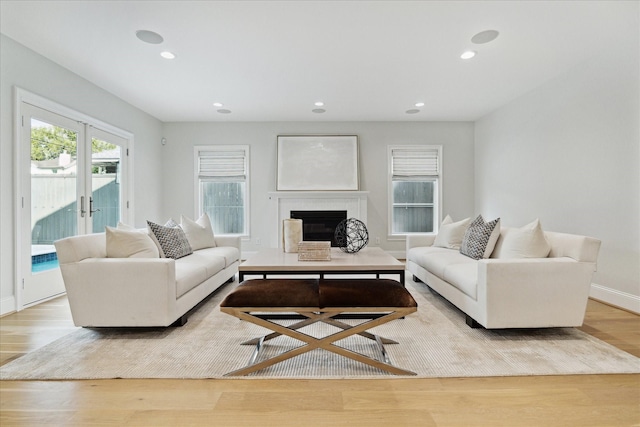 living room featuring recessed lighting, a fireplace, wood finished floors, baseboards, and french doors