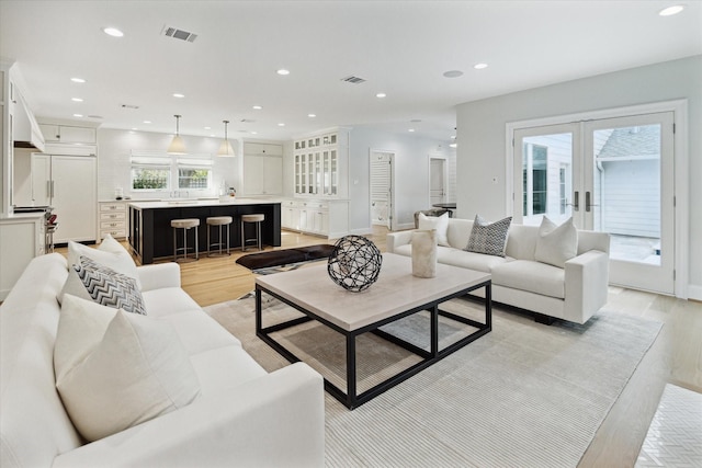 living area featuring french doors, light wood-type flooring, visible vents, and recessed lighting