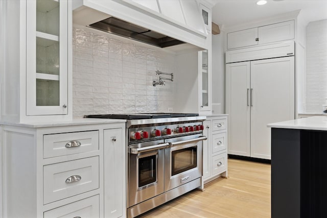 kitchen with light countertops, premium appliances, custom exhaust hood, and white cabinets