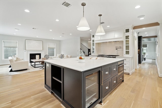 kitchen featuring light wood-type flooring, beverage cooler, visible vents, and white cabinets