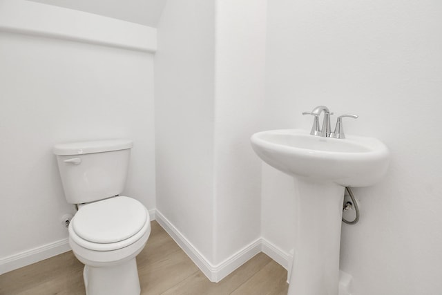 half bath with wood finished floors, toilet, and baseboards