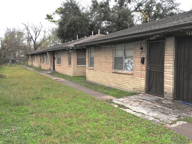 view of home's exterior with brick siding and a lawn