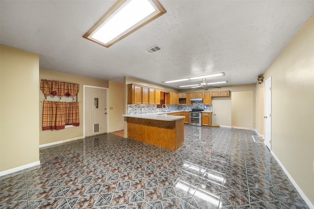 kitchen with a peninsula, double oven range, open floor plan, visible vents, and brown cabinetry