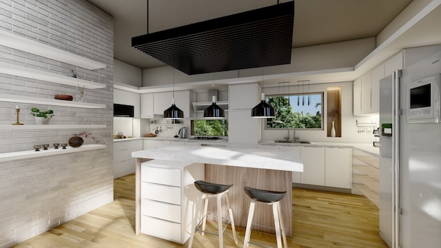 kitchen with light wood finished floors, white cabinets, brick wall, modern cabinets, and exhaust hood