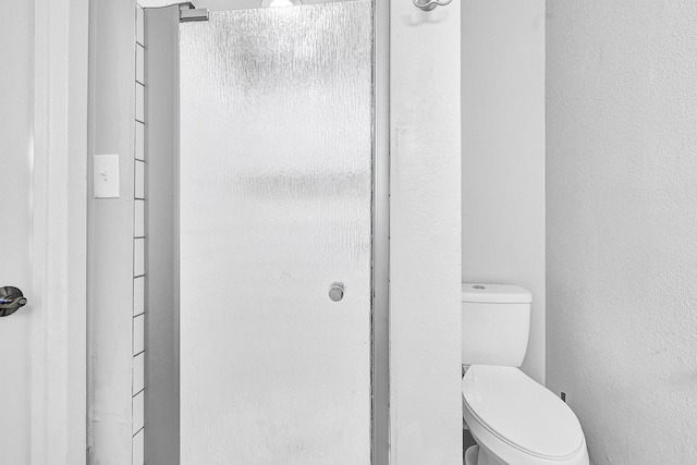 bathroom with a textured wall and toilet