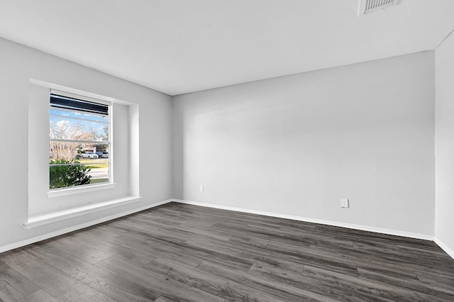 empty room with dark wood-style floors, baseboards, and visible vents