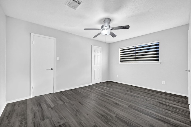 unfurnished room with dark wood finished floors, visible vents, ceiling fan, a textured ceiling, and baseboards