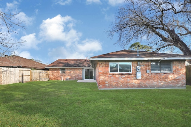 back of house with a yard, brick siding, and fence