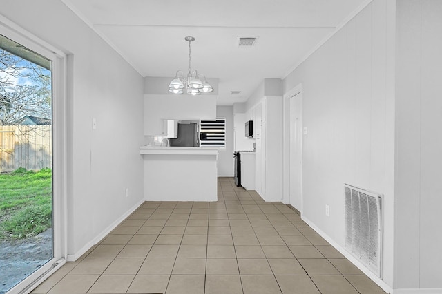 kitchen featuring light tile patterned floors, freestanding refrigerator, visible vents, and white cabinetry