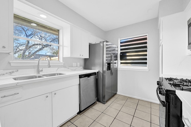 kitchen with stainless steel appliances, white cabinets, a sink, and light tile patterned floors