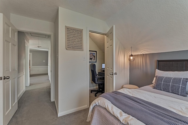 carpeted bedroom featuring lofted ceiling, a textured ceiling, attic access, and baseboards