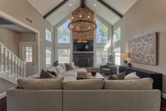 living area featuring visible vents, dark wood-style floors, beamed ceiling, a fireplace, and a chandelier