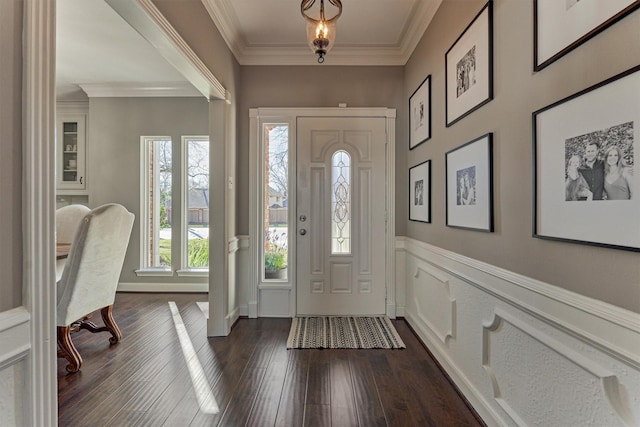 entrance foyer with dark wood-type flooring, crown molding, and a decorative wall