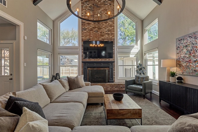 living area with a brick fireplace, visible vents, beamed ceiling, and wood finished floors