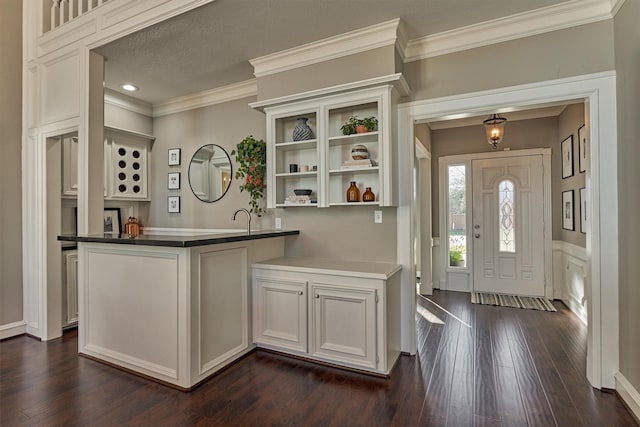 kitchen featuring dark wood-style floors, crown molding, open shelves, dark countertops, and a peninsula