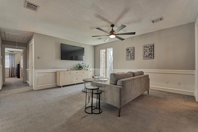 living room with visible vents, a wainscoted wall, carpet flooring, and attic access