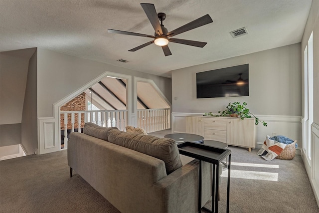 living room with carpet floors, a ceiling fan, visible vents, and a textured ceiling