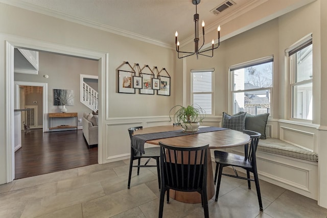 dining space with a notable chandelier, a decorative wall, visible vents, stairs, and ornamental molding