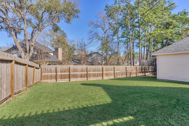 view of yard with a trampoline and a fenced backyard