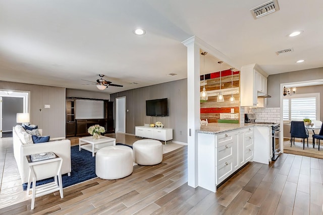 living area with ceiling fan, visible vents, and wood finished floors