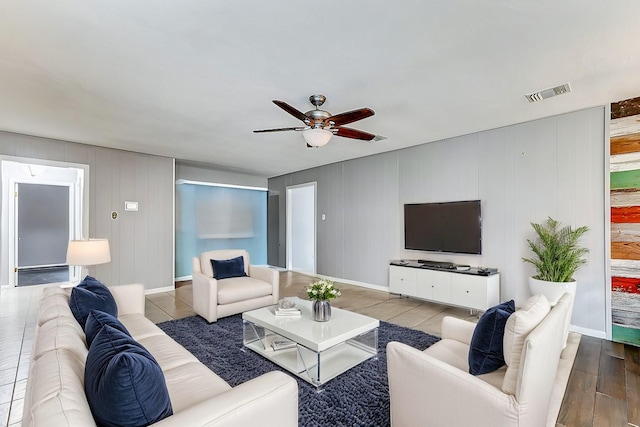 living area with a ceiling fan, baseboards, visible vents, and wood finished floors