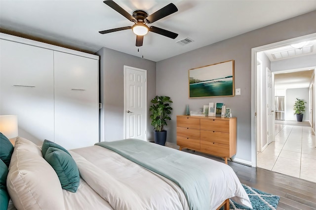 bedroom featuring baseboards, light wood finished floors, visible vents, and a ceiling fan