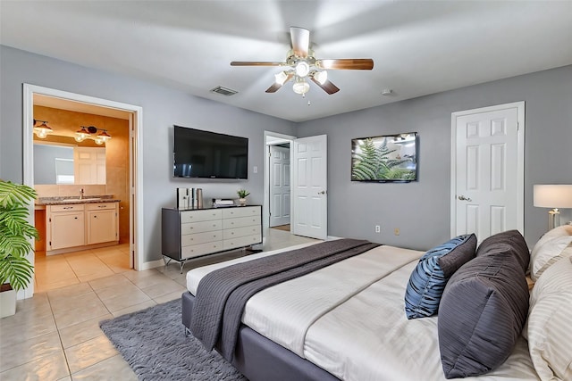 bedroom with light tile patterned floors, connected bathroom, a sink, visible vents, and a ceiling fan