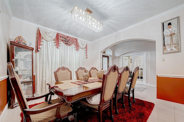 dining area featuring arched walkways, crown molding, and a textured ceiling