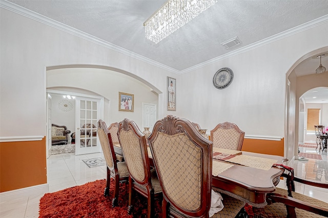 dining space with light tile patterned floors, visible vents, a textured ceiling, and ornamental molding