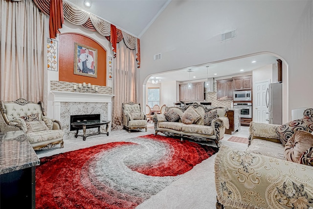 living area featuring visible vents, a premium fireplace, arched walkways, and light colored carpet