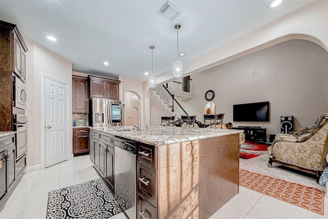 kitchen with visible vents, arched walkways, stainless steel appliances, a sink, and light tile patterned flooring