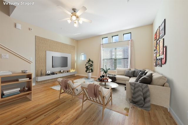 living room with a ceiling fan, baseboards, and wood finished floors