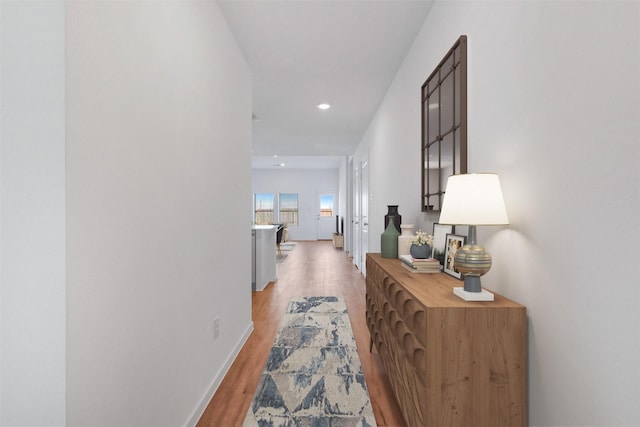 corridor featuring recessed lighting, light wood-style flooring, and baseboards