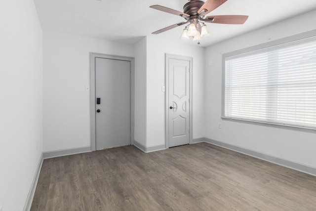 empty room featuring ceiling fan, baseboards, and wood finished floors