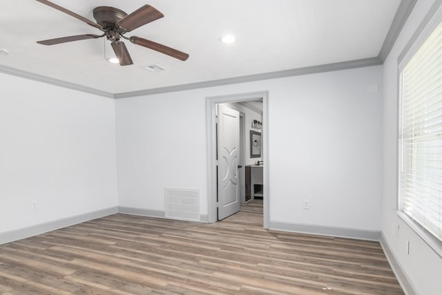 spare room featuring visible vents, crown molding, baseboards, and wood finished floors