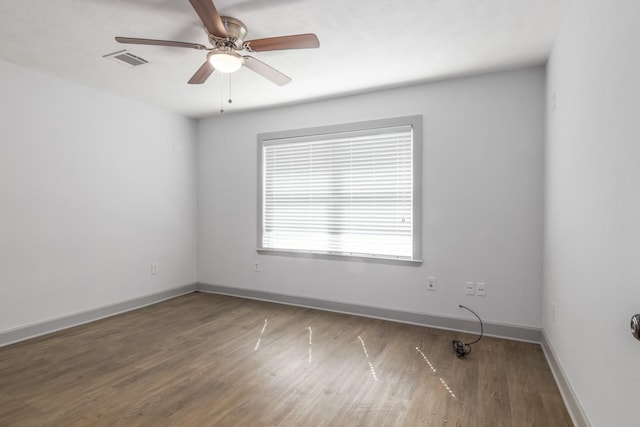 empty room featuring baseboards, visible vents, ceiling fan, and wood finished floors