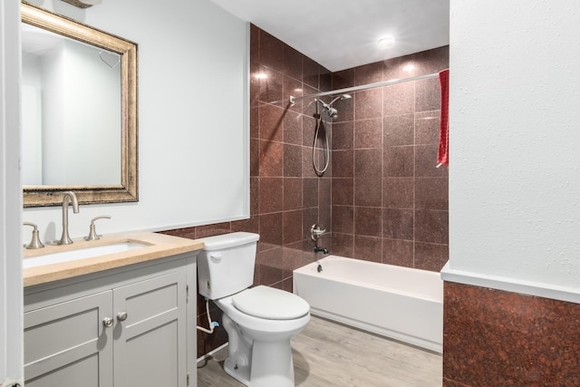 full bath with shower / bathtub combination, toilet, wood finished floors, vanity, and tile walls