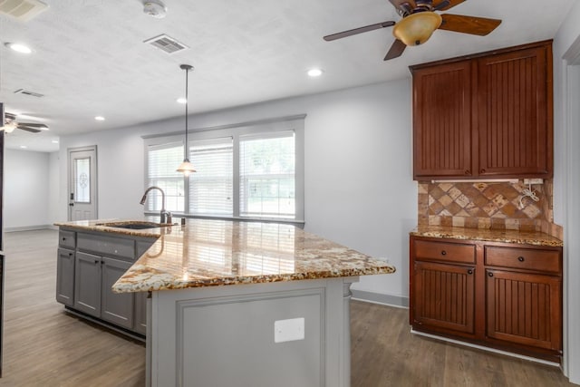 kitchen featuring tasteful backsplash, visible vents, a sink, and wood finished floors