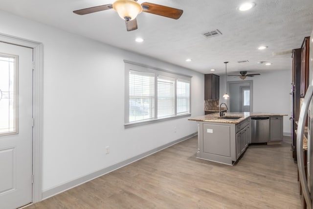 kitchen featuring visible vents, light wood-style flooring, a sink, dishwasher, and baseboards