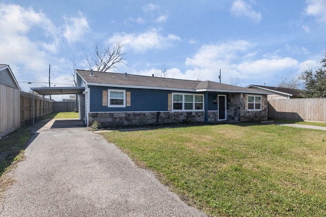 single story home featuring driveway, stone siding, fence, a front lawn, and a carport