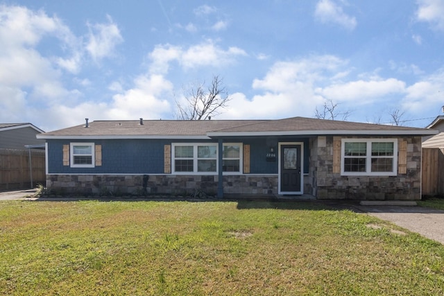 single story home with stone siding, a front lawn, and fence