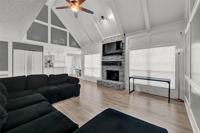 3610 Cypresswood Dr, Spring, TX 77388 - living room featuring a ceiling fan, beam ceiling, a fireplace, light wood-style flooring, and high vaulted ceiling