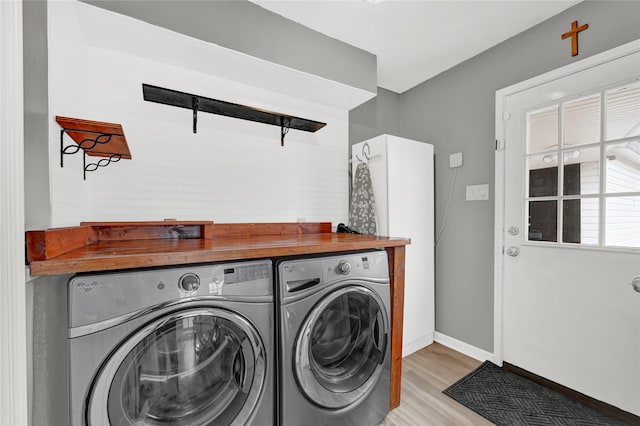 washroom featuring laundry area, light wood finished floors, independent washer and dryer, and baseboards