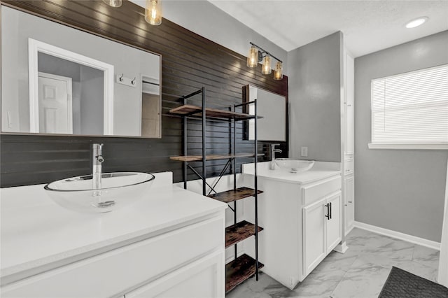 bathroom featuring baseboards, a sink, marble finish floor, and two vanities