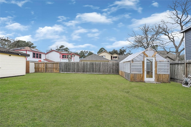 view of yard with an outdoor structure, a fenced backyard, and a greenhouse