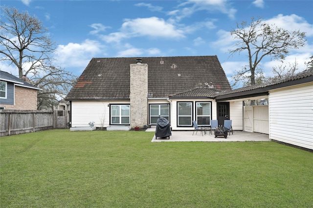 rear view of property with a fenced backyard, a chimney, a patio area, a lawn, and an outdoor fire pit